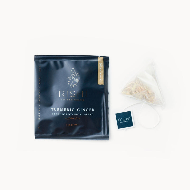 A bag of Turmeric Ginger tea with a Rishi Tea & Botanicals tea bag next to it.