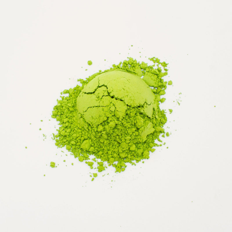 A pile of vibrant green Nishi San's Matcha Kanayamidori from Rishi Tea & Botanicals on a white background exudes a subtle floral aroma.