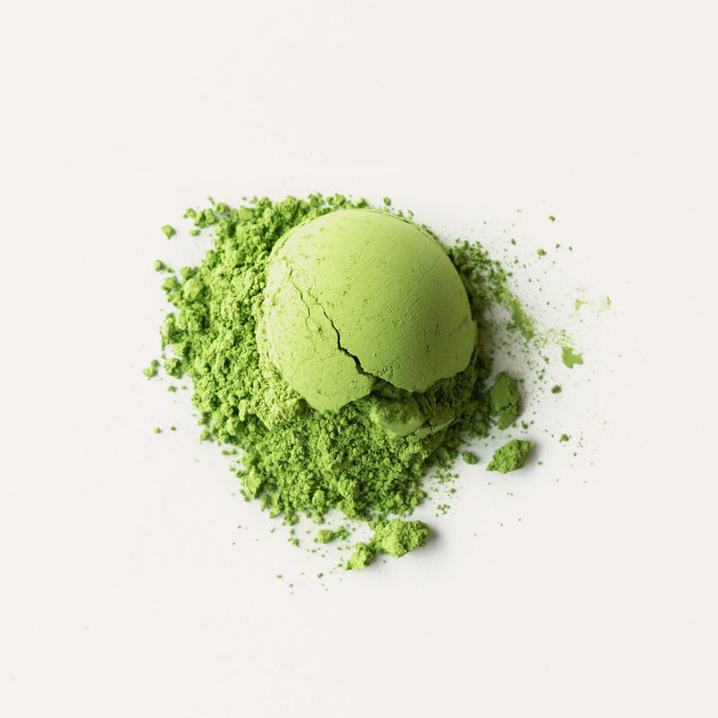 A dome-shaped mound of Rishi Tea & Botanicals' premium Matcha Ujihikari, with some of the vibrant green powder spread around it on a white surface.